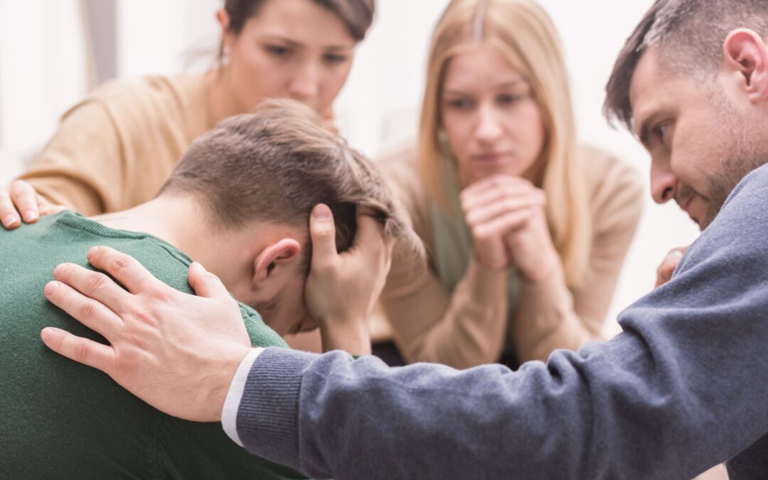 Supportive group offering comfort to a person struggling